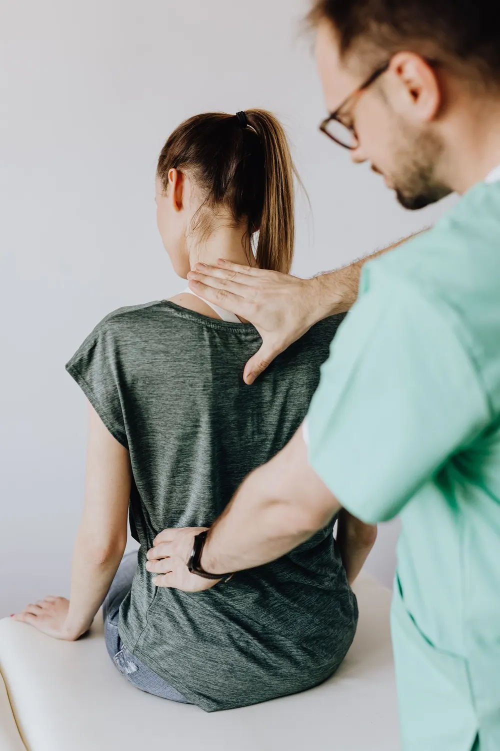 Ostéopathe vérifiant la posture du dos d’une femme assise, en tenue de ville